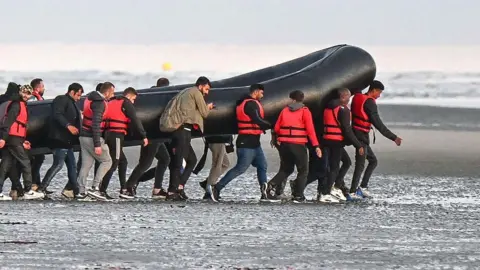 Getty Images Migrants in France carry a dingy in an attempt to cross the Channel