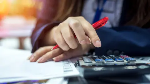 Getty Images Picture showing hands of someone with a calculator working on their finances