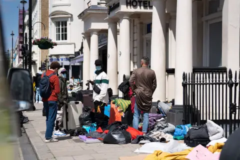 PA Media Migrants outside a hotel in Pimlico, London