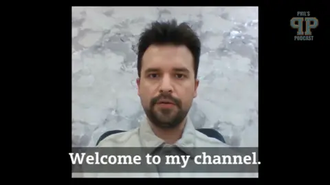 YouTube A man in front of a plain backdrop with the subtitle 