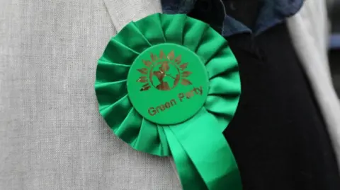 PA Media A Green Party rosette