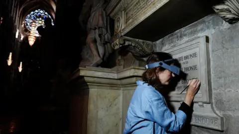 PA Conservator Lucy Ackland adds the finishing touches to the memorial to Charlotte, Emily and Anne Bronte at Poets' Corner in Westminster Abbey in London.