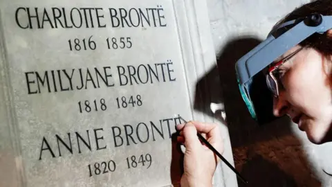 PA Conservator Lucy Ackland adds the finishing touches to the memorial to Charlotte, Emily and Anne Bronte at Poets' Corner in Westminster Abbey in London