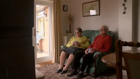 Margaret and David Fee on the sofa with a cup of tea