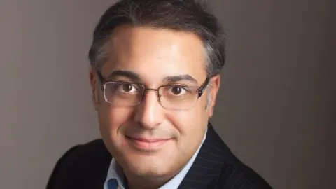 Mr Yaser Jabbar seen in an undated professional portrait photograph wearing a smart suit and glasses