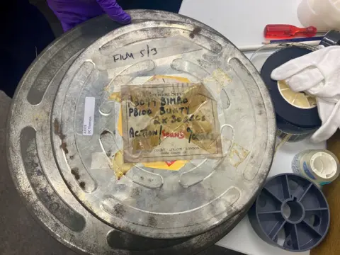 The large round container for the old films is battered and rusted