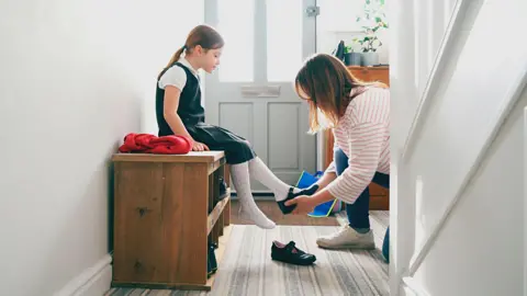 Getty Images Mother putting shoes on child  - stock shot.