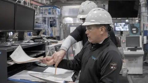 Norsk Hydro Appearing confused two factory staff look at paperwork at a Norsk Hydro plant