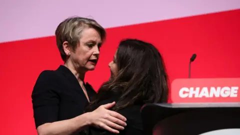 Reuters Home Secretary Yvette Cooper embraces Pooja Kanda on stage at Labour conference