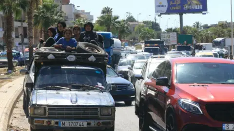 Getty Images A family sits with their belongings in the back of a truck as they wait in a traffic jam in the Lebanese city of Sidon