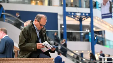 Getty Images A delegate at the Conservative party conference reading the conference agenda