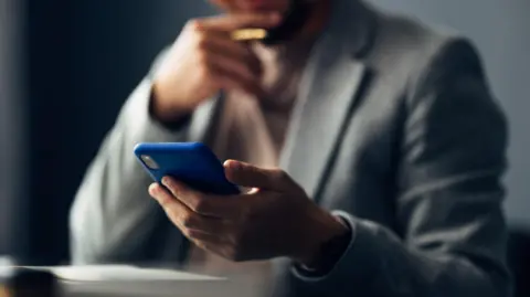 Getty Images Anonymised man looks at phone