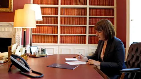 PA Media Rachel Reeves at her desk at no 11 Downing Street, writing on paper