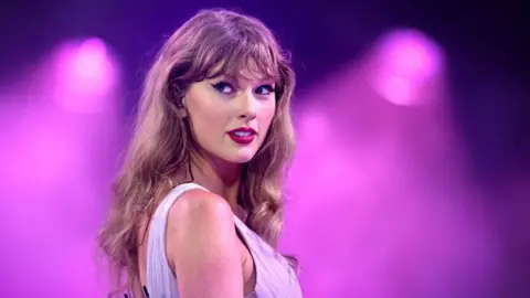 Getty Images Taylor Swift on stage at Wembley with a purple background