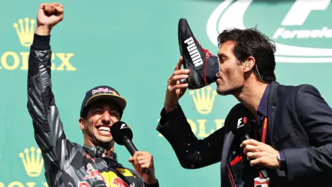 Getty Images Daniel Ricciardo celebrates as Mark Webber does a shoey.