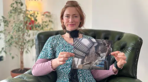 Maxine Sharples Maxine Sharples sitting on a sofa and holding up a photo.