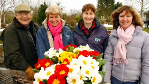 Tern TV Jim McColl on left of photo smiling with three women co-presenters. There is a bouquet of white and red flowers in front of them