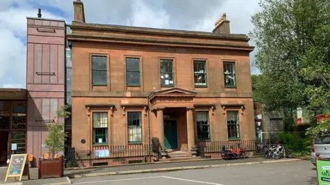 BBC A Victorian mansion building in Dumfries made out of local sandstone with a few bicycles parked outside and a tree to one side of it