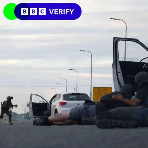 Getty Images Journalists take cover behind cars as Israeli soldiers take position during clashes with Palestinian fighters near the Gevim Kibbutz, close to the border with Gaza on 7 October, 2023