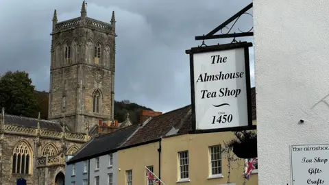 A view over Axbridge town square, towards the old church. In the foreground, a sign reads 