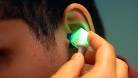 BBC News A device is put in a student's ear to check hearing