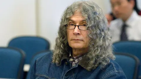 Getty Images Serial killer Rodney Alcala sits silently after hearing the death sentenced pronounced by Judge Francisco Briseno in a Santa Ana courtroom March 30, 2010 - he is wearing a denim jacket, checked shirt and has long curly grey hair