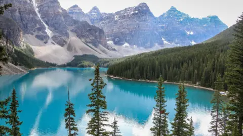 Getty Images A mountain and blue lake surrounded by trees in Canada