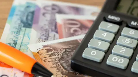 Getty Images British pounds, calculator, a ball-point pen and Bank of England notes.