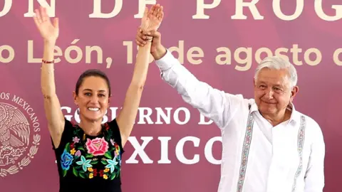 Getty Images Andrés Manuel López Obrador holding up Claudia Sheinbaum's arms at an event back in August