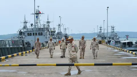 Getty Images Cambodian navy personnel walk on a jetty in Ream naval base, with Navy vessels in the background