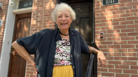 BBC Judy Aleksalza smiling outside of her home.