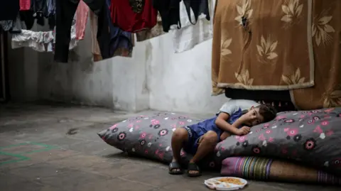 Reuters A displaced boy rests in a school in Beirut which provides temporary shelter to the families. A plate of food sits at his feet as he leans to one side resting his head on a pillow