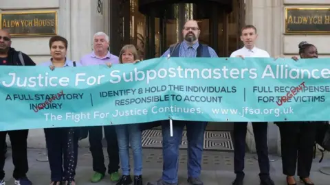 EPA Post Office sub-postmasters stand with a Justice For Sub-Postmasters Alliance banner in their fight for justice in central London