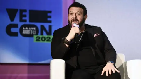 Getty Images Adam Richman in a black suit jacket and t-shirt speaking during VeeCon 2024