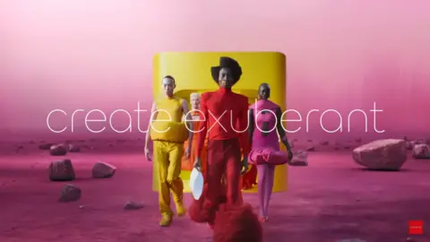 Jaguar models in bright coloured clothes walk across a pink landscape