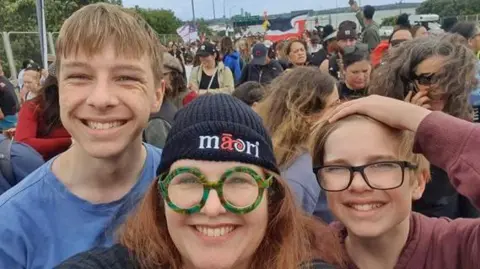 Danielle Moreau A smiling woman takes a selfie with her two sons