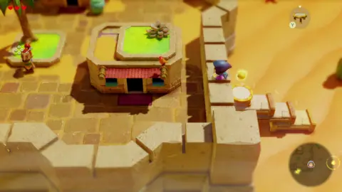 Nintendo Screenshot shows the main character scaling the wall of a desert settlement. At the right of the screen a stack of three beds with a small trampoline placed on top of the uppermost bed can be seen.