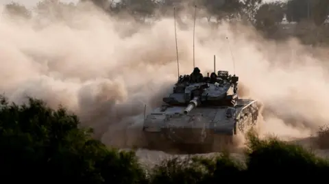 Reuters An Israeli tank manoeuvres near the Israel-Gaza border (15 October 2024)