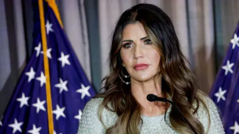 Getty Images Kristi Noem, wearing a silvery-white dress, looks out during a speech at the Calvin Coolidge Foundation conference 