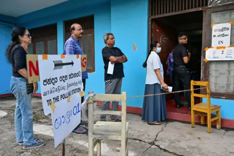 Getty Images People queue at a polling station before casting their ballots to vote in Sri Lanka's parliamentary election in Colombo