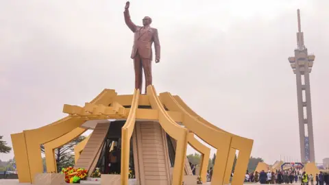 AFP Yellow arches surround the mausoleum of Patrice Lumumba in Kinshasa. His statue stand atop the structure.