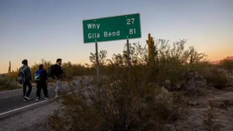 AFP Immigrants from India walk into the United States after crossing the US-Mexico border on 7 December 2023 in Lukeville, Arizona.