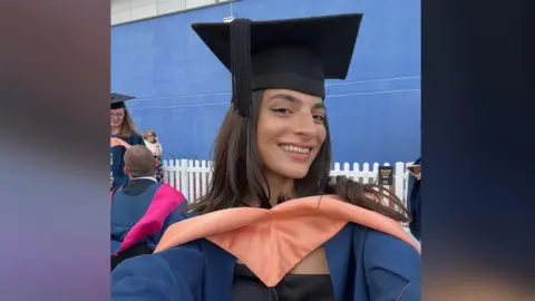 Buket Komur Buket Komur is wearing her university graduation mortar board and gown