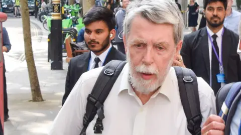 Getty Images Gareth Jenkins wearing a white shirt and carrying a rucksack outside the Post Office Inquiry