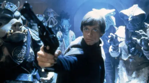 Getty Images Mark Hamill pointing a gun surrounded by monster creatures in Star Wars: Episode VI - Return of the Jedi