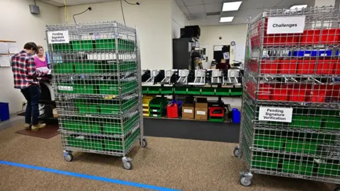 Getty Images Trays of ballots that have been challenged or require signature verification at a ballot processing site in California