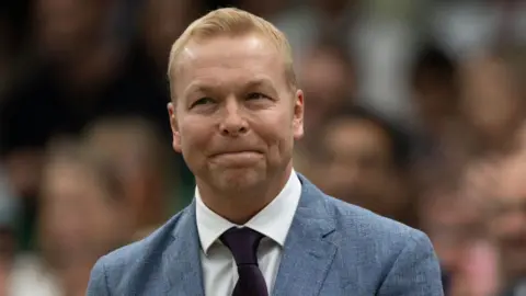 Getty Images Sir Chris Hoy wears a light blue suit and maroon time and is facing the camera while photographed in the royal box at Wimbledon Centre Court in 2024