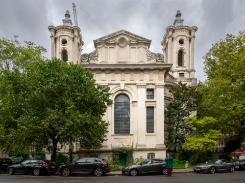 Historic England Smith Square Hall with trees and cars parked outside under grey skies