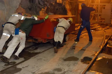 Getty Images Legally employed miners push a box of explosives below ground at a gold mine in South Africa on 27 October 2005