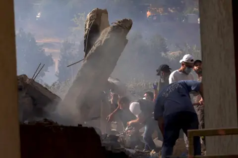 Darren Conway / BBC Samir and his crew look for bodies in the rubble.